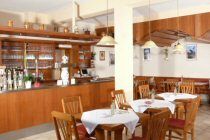 Gemütlicher Gastraum mit Holzmöbeln und Biertheke im Hintergrund
