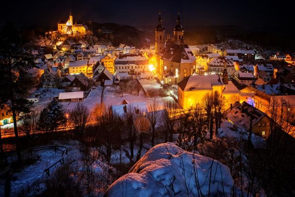 Blick auf ein Dorf bei Nacht mit beleuchteten Straßen.