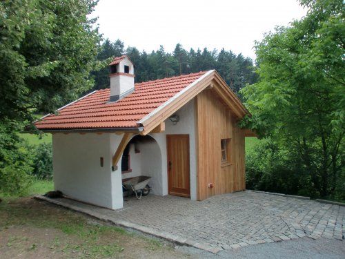 Auf einer gepflasterten Fläche steht,umgeben von Bäumen und Wiesen, der Bürgerbackofen.