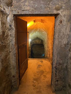 Tonnengewölbte Kellergänge aus steinernen Wänden und Böden mit hohen Decken und weiten Verzweigungen bilden die Gewölbekeller unterhalb des heutigen Posthotel Johannesberg im hessichen Lauterbach. Die alten Wände sind marode und der boden ist feucht. Spärliches Licht beleuchtet die Gänge.