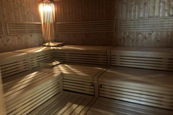 Eine Sauna mit zwei übereinanderliegenden, L-förmigen Bankreihen aus Holz.