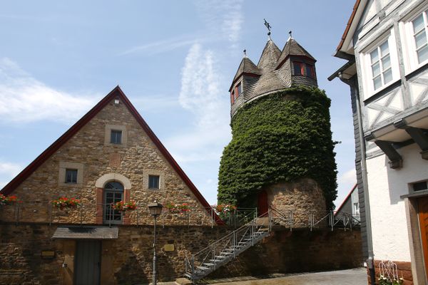 Ein Steinhaus oberhalb der Stadtmauer, das fast nur aus dem Giebel besteht. Im Keller führt eine schlichte Holztür hinein, ins Obergeschoss, dass über eine Metallmauer und einen Gang auf der Stadtmauer erreichbar ist, führt eine Bogentür, gerahmt von drei schlichten Fenstern, nach innen. Rechterhand steht ein Steinturm und verschiefertem Spitzdach mit zwei Gauben, der fast völlig von einer Grünpflanze umrankt ist. Im Untergeschoss führt eine kleine rote Bogentür ins Innere.