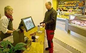Auf dem Bild ist ein Kunde an der Kasse des Ladens zu sehen.