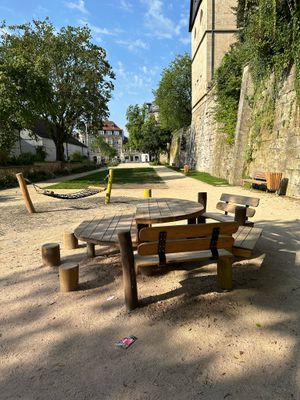 Das Bild zeigt eine Sitzgruppe und eine Hängeschaukel am Spielplatz im Stadtgraben in Kronach.
