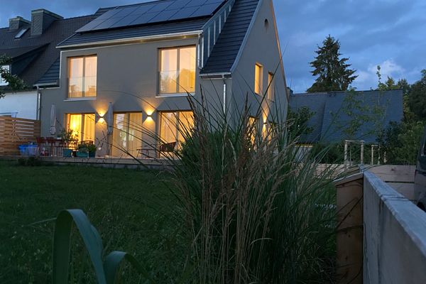 Das Bild zeigt die Außenansicht des Hauses bei Abendstimmung vom Garten aus