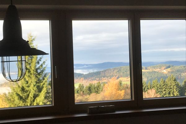 Durch ein Dreifach-Fenster blickt man auf eine weitläufige, wunderschöne Landschaft aus bunten Wäldern und sanften Hügeln.