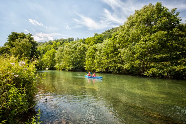 Ein blaues Kanu gleitet auf dem Fluss entlang.