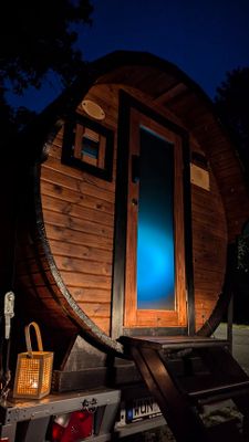 Auf dem Bild ist die mobile Fass-Sauna bei Nacht von außen zu sehen.