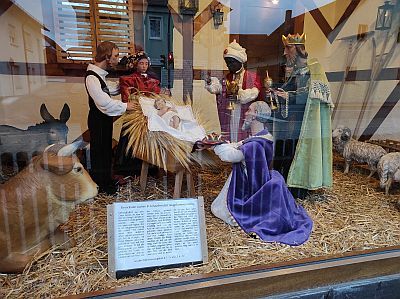 Die Drei Königen knien vor dem Jesuskind mit seinen Eltern. Links ragen der Esel und der Ochs ins Bild.