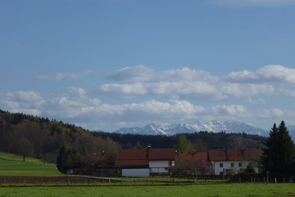 Auf dem Rückweg entlang des östlichen Ortsrands von Eberfing lohnt sich ein Blick zurück - die Häuser von Eberfing mit den dahinter aufragenden Gipfeln der Bayerischen Alpen.
