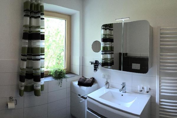 Geschmackvolles Badezimmer mit Fenster und gestreiftem Vorhang sowie Handtuch-Heizkörper, Waschbecken mit passendem Unterschrank, Bad-Spiegelschrank mit Licht, Kosmetikspiegel und Fön.