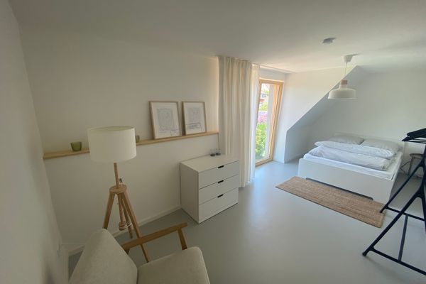 Blick in das Schlafzimmer mit Sitzgelegenheit im Vordergrund und Doppelbett im Hintergrund