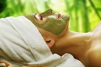 Auf dem Bild ist eine Frau mit einer Gesichtsmaske und einem Handtuch um ihre Haare zu sehen.