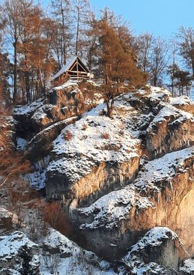 Blick auf das vom Schnee angezuckerte Felsmassiv, auf dem der hölzerne Aussichtspavillon steht.