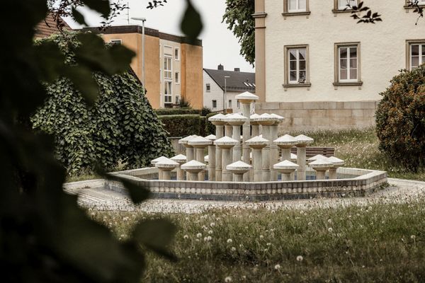 Geometrisch gestaltete Brunnenanlage aus Stein in einer Grünfläche im Zentrum von Schönwald.