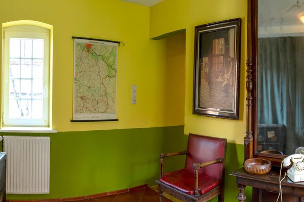 Flur mit Stuhl, Kommode mit Spiegel, Fenster und Wandbild.
