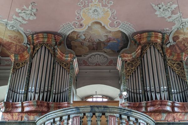 Das Bild zeigt den Innenraum der Wallfahrtskirche Mariä Geburt in Glosberg. Man sieht Sitzbänke und prunkvolle Altäre, Gemälde und Statuen.