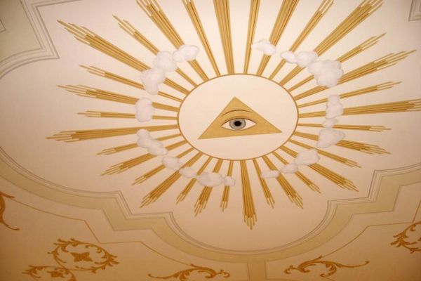 Die Deckenbemalung der Kirche zeigt ein einzelnes Auge im Zentrum eines goldenen Strahlenkranzes, der von Wolken durchbrochen wird.