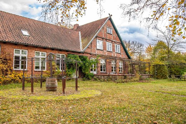 Haus mit Fachwerkfassade, Garten mit Wiese, Bäumen und Sitzmöbeln im Außenbereich.