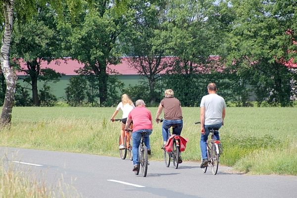 Menschen fahren mit Fahrrädern auf einer Straße in Richtung Niendorf I in der Lüneburger Heide