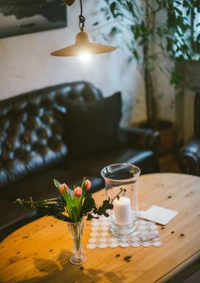 Ein gemütlicher Wohnbereich mit Ledersofa, Holztisch und einer Vase mit Tulpen.