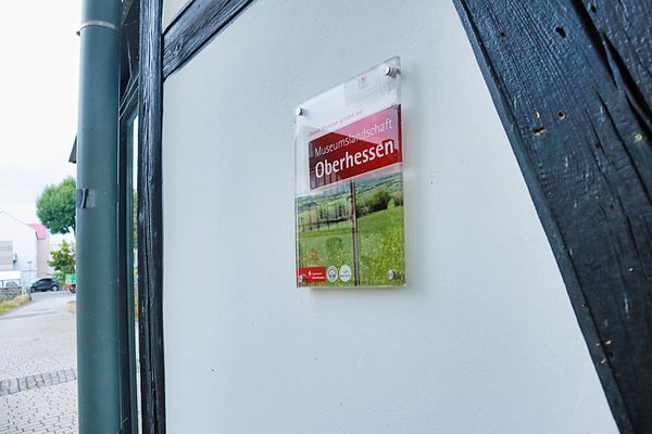 Zu sehen ist ein Schild, das darauf verweist, dass das Schlossmuseum Romrod zur Museumslandschaft Oberhessen gehört. Das Schild befindet sich an der Außenwand eines Fachwerkhauses.