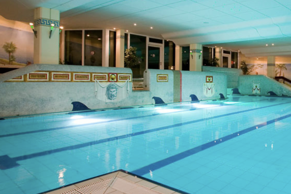 Das Hallenbad "Römerlagune" verfügt über Wasserliegen und ein beleuchtetes Schwimmbecken. Die Wände sind mit verschiedenen Motiven und Bildern dekoriert.
