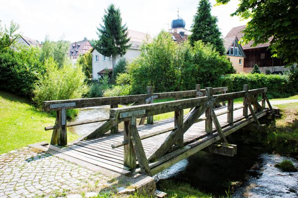 Eine hölzerne Brücke führt über einen Bach.