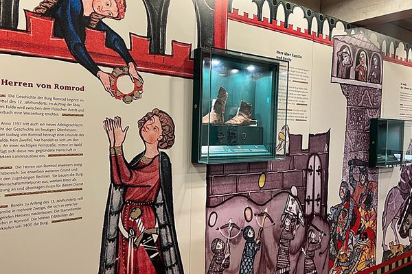 Eine Infotafel auf einer ganzen Wand zu den Herren von Romrod mit historischen Illustrationen und dazwischen originalen Exponaten.