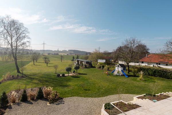 Garten der Ferienwohnung Bergfeld mit einem kleinen Spielplatz und einigen Bäumen; der Himmel ist blau
