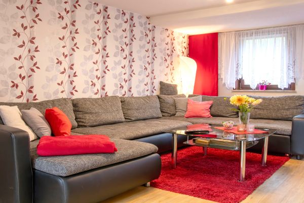 Großes Ecksofa mit Kissen vor einem Couchtisch auf rotem Teppich im Wohnzimmer