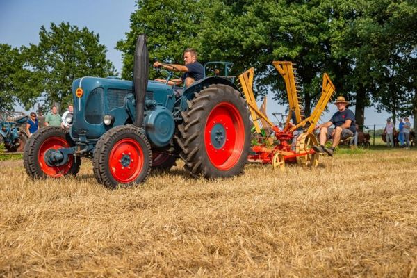 blauer Trecker mit anfgehängtem Ackergerät im Einsatz bei einer Vorführung