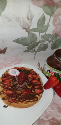 Auf dem Bild ist eine Waffel mit Nutella und Erdbeeren zu sehen.