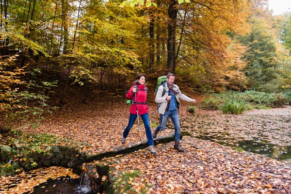 Zwei Wanderer die über einen kleinen Bach steigen