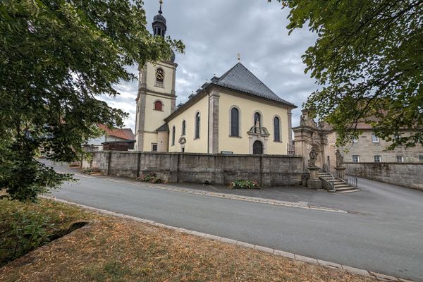 Das Bild zeigt die Außenansicht der Wallfahrtskirche Mariä Geburt in Glosberg. Man sieht die Kirchturmspitze und die Nebengebäude der Kirche.