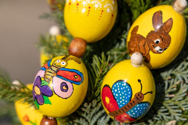 Vier gelbe, bemalte Eier mit Schmetterlings- und Hasenmotiven.