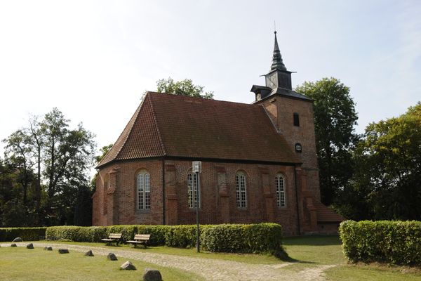 Außenansicht der Stellichter Kirche, davor ist eine große Wiese mit Hecken und Sitzbänken