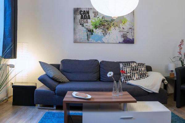 Sofa mit Kissen vor einem Couchtisch mit Dekoration in einem Wohnzimmer