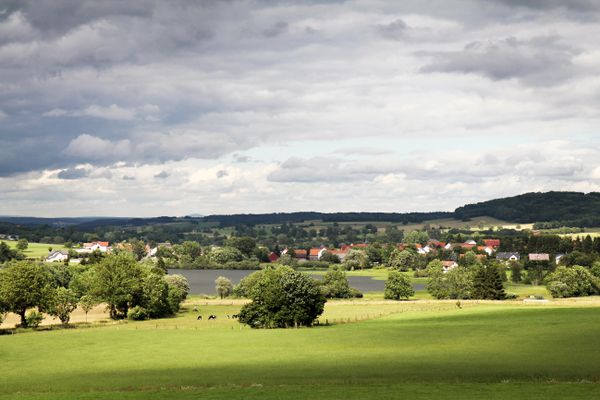 Inmitten üppig grüner Wiesen liegt der kleine Ober-Mooser-See, der auf der gegenüberliegenden Seeseite von dem kleinen Ort Ober-Moos touchiert wird. Der Blick geht weit ina sanft geschwungene Land des Vogelsberges. Es ist ein wolkenbehangener Tag, der wohl noch Regen mit sich bringt.