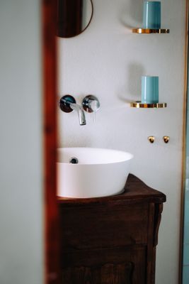 Auf dem Bild ist ein Waschbecken in einem Bad zu sehen. Darunter befindet sich ein Waschbecken-Unterschrank auf dunklem Holz.