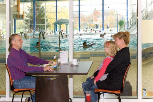 Ein Paar mit kleinem Mädchen sitzt an einem Tisch mit Blick in die Spessart Therme