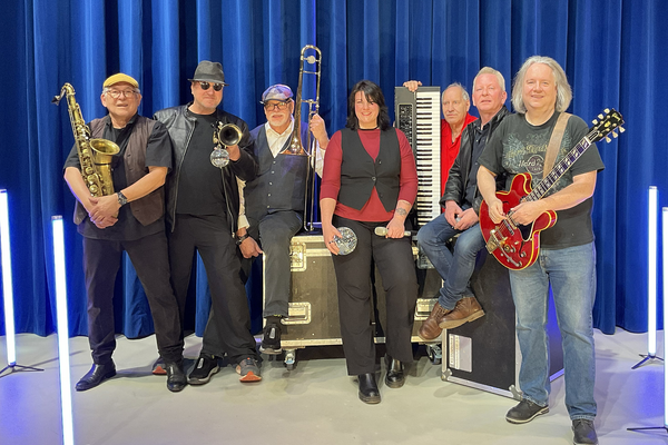 Die Band Soul & Gebläse steht vor einem blauen Vorhand. In ihren Händen die Musikinstrumente