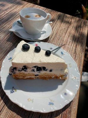 Kaffeegedeck mit Torte und Cappuccino auf der Terrasse des Dielencafés