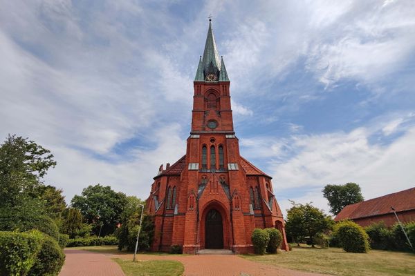 Backsteinkirche Marienkirche in Suhlendorf im Landkreis Uelzen in der Lüneburger Heide mit hohem Turm und Vorplatz.