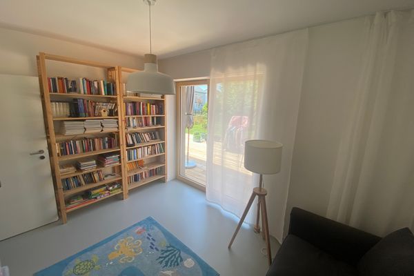 Blick in die Bibliothek mit großem Bücherregal und Sitzgelegenheit