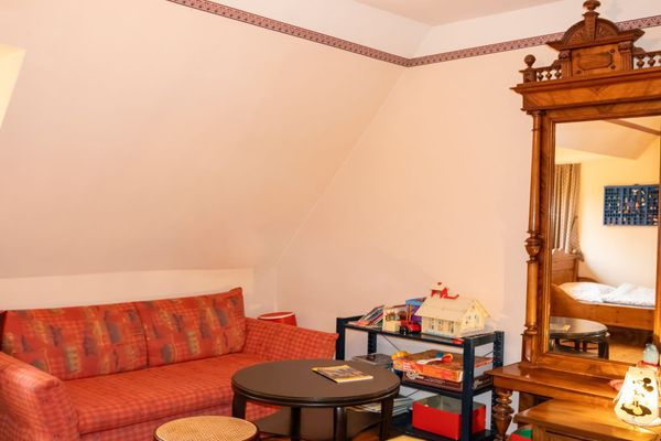 Sofa mit Tisch davor, daneben ein Regal mit Gegenständen und ein großer Spiegel an der Wand.