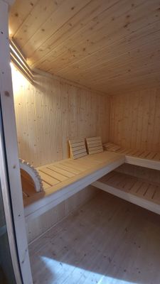 Holz-Saunaraum mit drei Holzliegen.