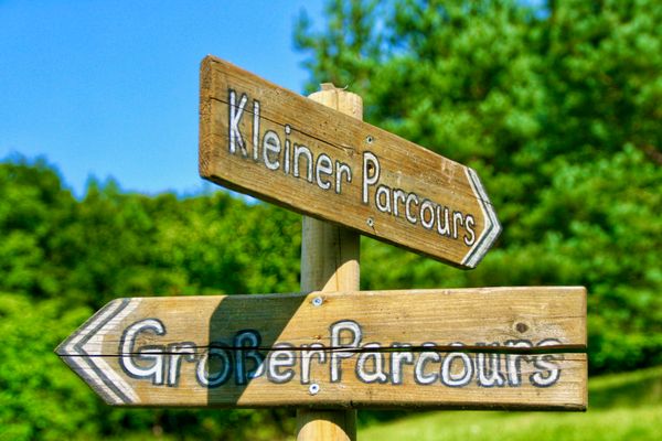 Zwei Richtungsanzeiger aus Holz, welche die Richtung zum Kleinen- und großen Parcours anzeigen