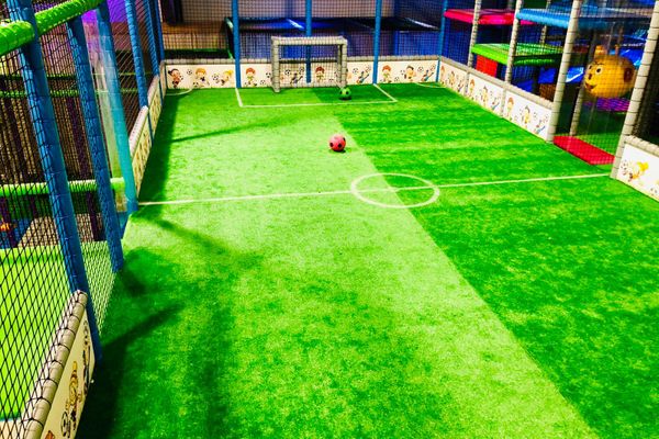 Indoorhockeyfeld mit flauschigem Grün am Boden.