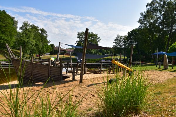 Spielecke im Standbad Dorfmark, im Vordergrund steht eine Wippe im Hintergrund ist das Spielgerüst in Form eines Schiffes